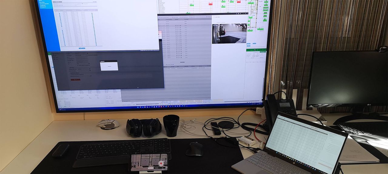 Felügyeleti munkaállomás: nagy képernyőn rendszerkezelő szoftver élőképpel, mellette laptop és asztali telefon.